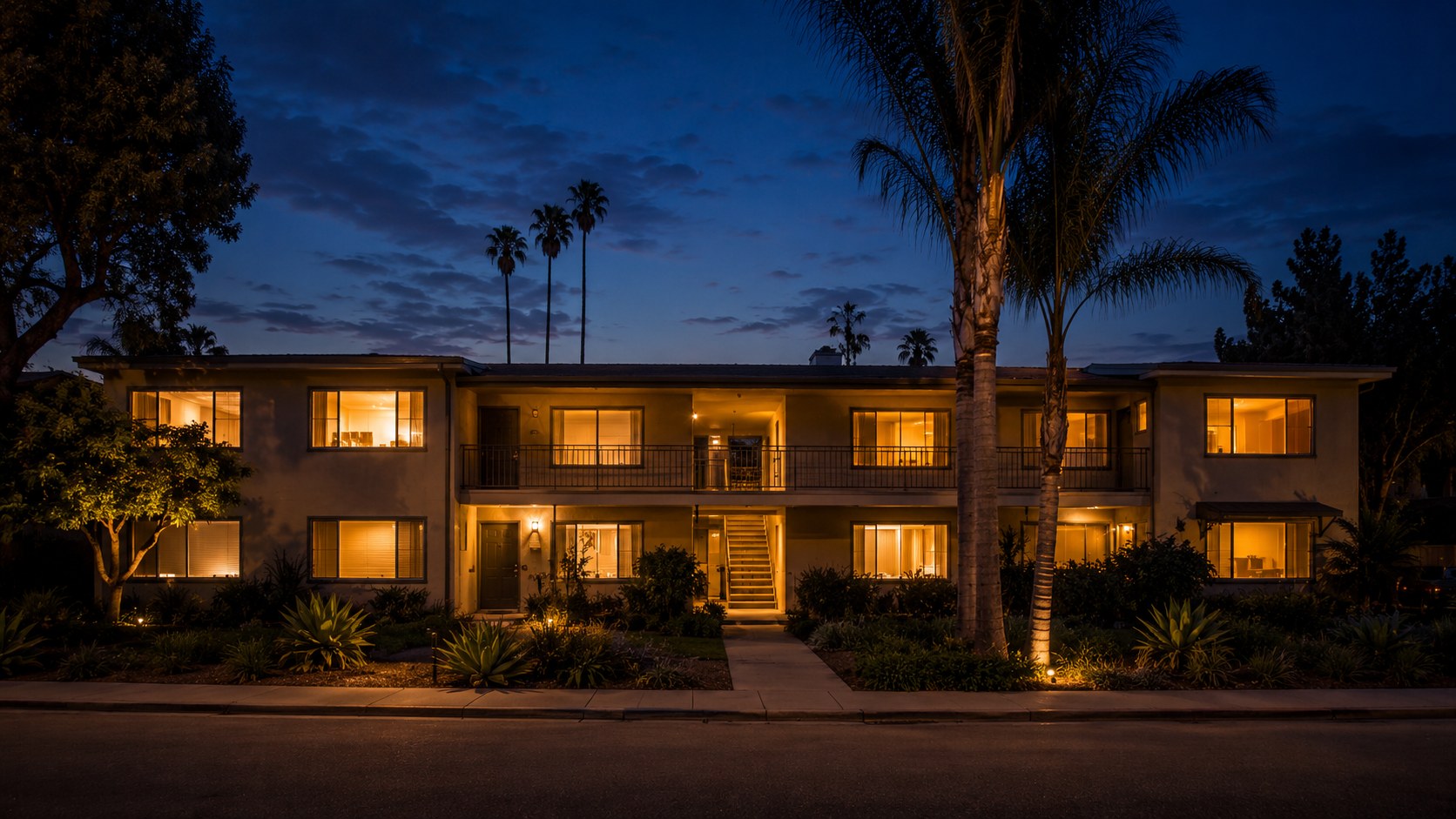 Small multifamily building at dusk with lit windows