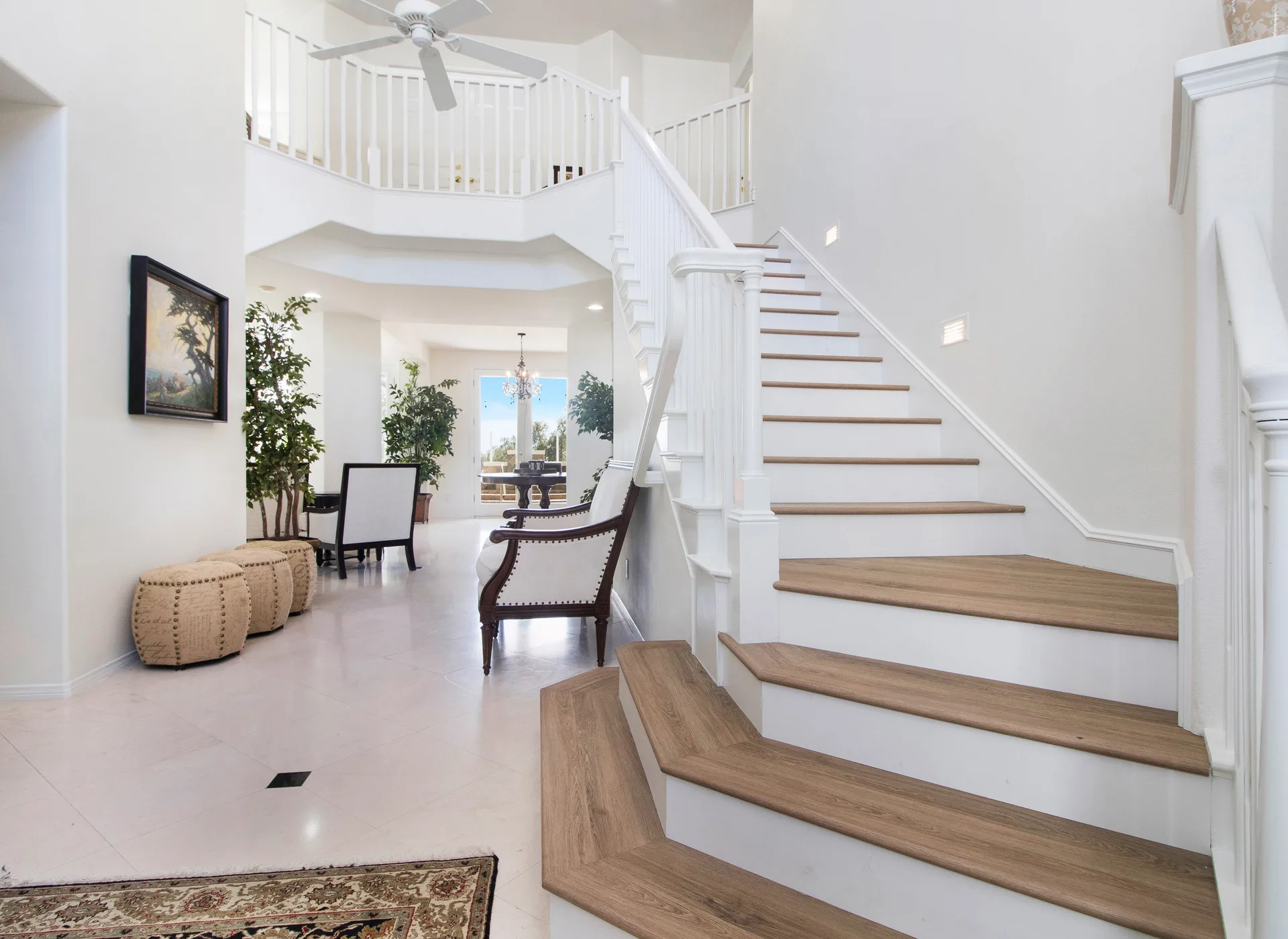 A double-height entry hall with a curved staircase and a balustraded landing above