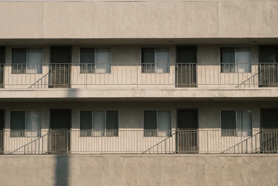 A repeating rhythm of windows and stair rails across a two-storey stucco elevation