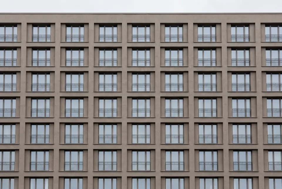 A regular grid of windows with deep reveals across a flat stucco elevation